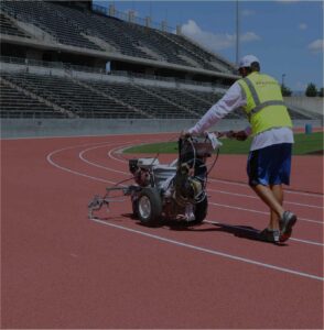 paragon sports employee lays down stripes on track field